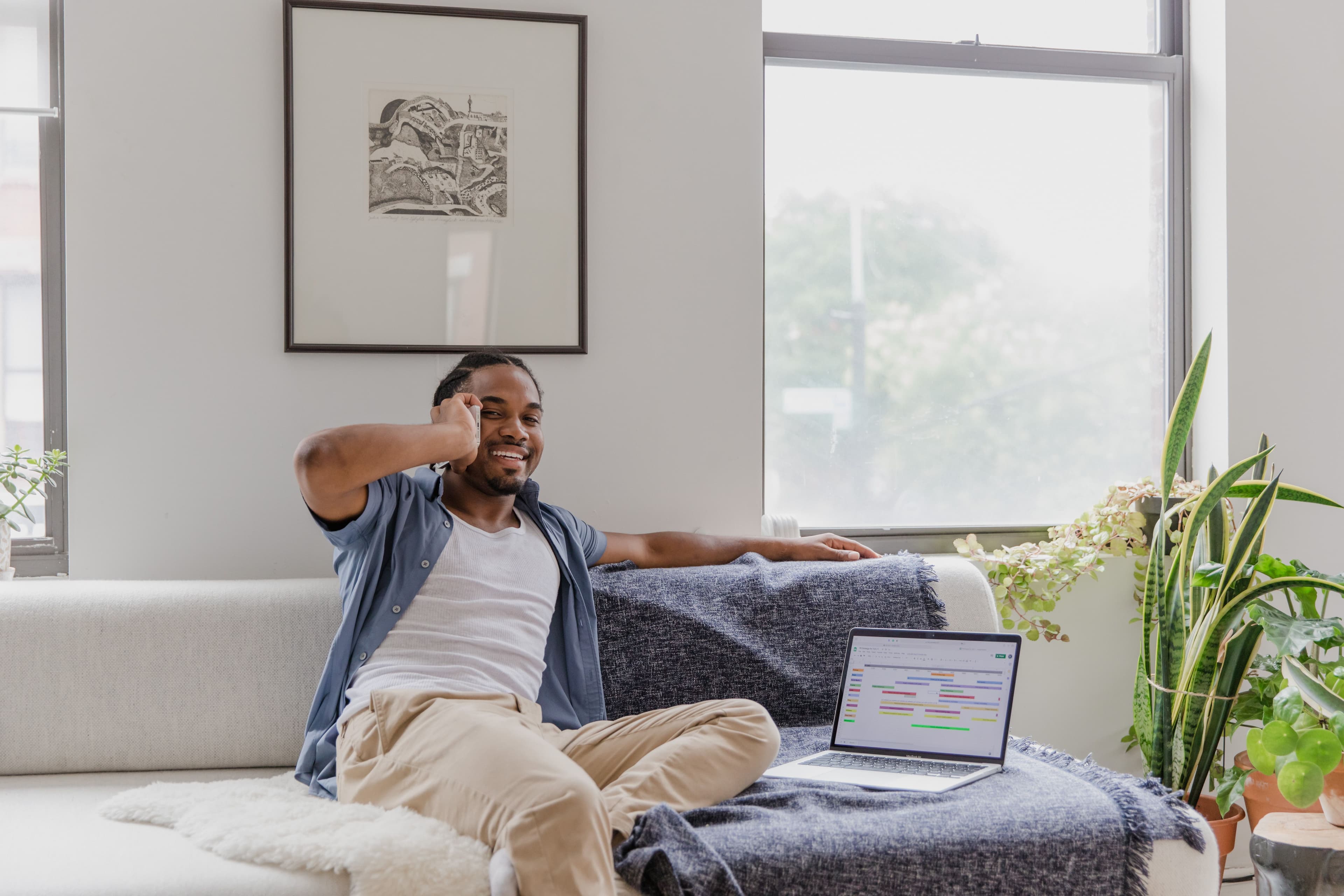 Man laughing on the phone with a colorful calendar on a laptop screen